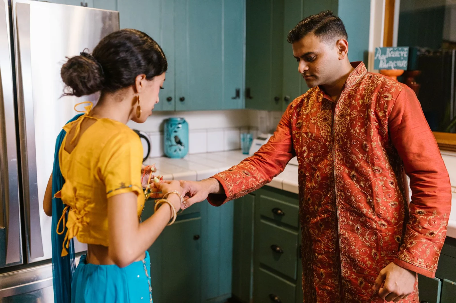 A couple in traditional Indian attire interacting in a modern kitchen environment.