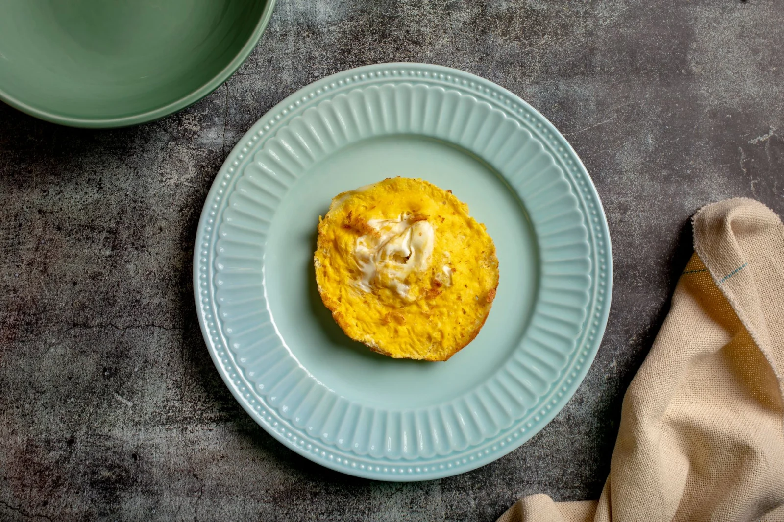Explore a delicious Chitoi Pitha topped with egg, representing authentic Bangladeshi cuisine on a rustic table setting.