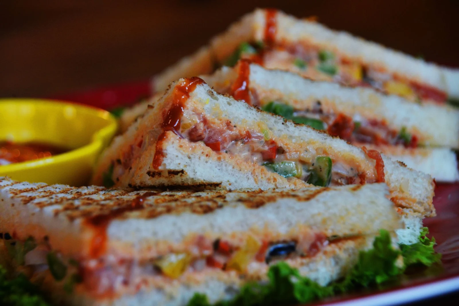 Close-up of a grilled vegetable sandwich with lettuce and sauce, perfect for a healthy snack.