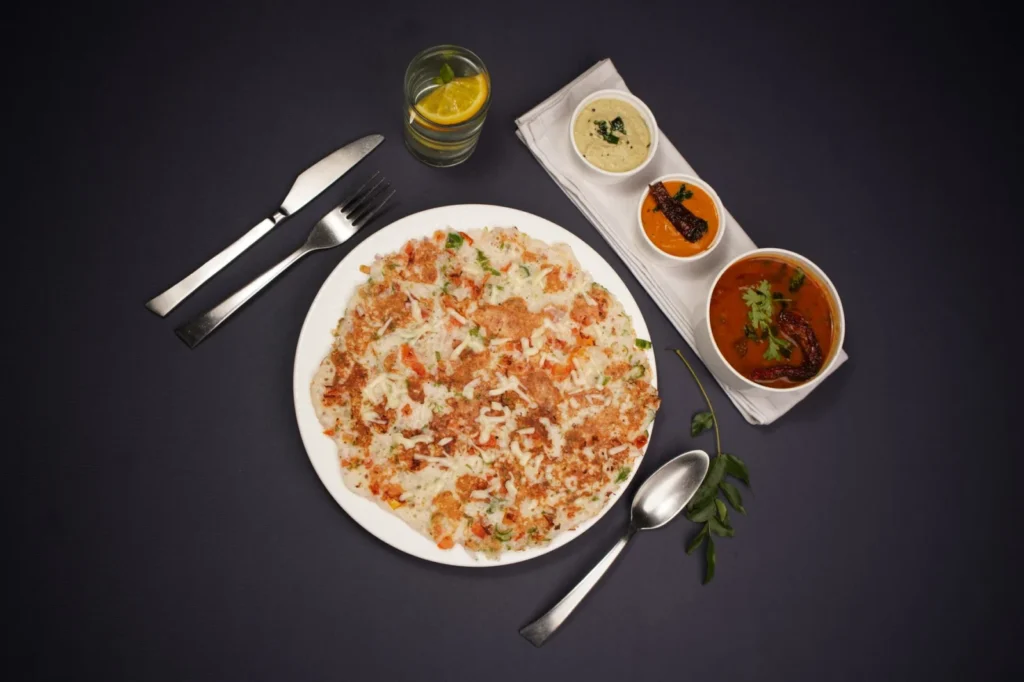 Top view of South Indian dosa served with various chutneys on a black background.
